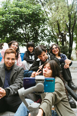 Fototapeta premium Group of cheerful Hispanic university friends laughing and posing for a vlog with a smartphone on a gimbal