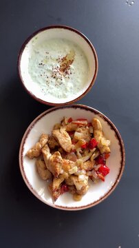 Top-down view of sizzling chicken fajitas with creamy tzatziki, fresh ingredients, rustic wooden table, vibrant Mediterranean dining