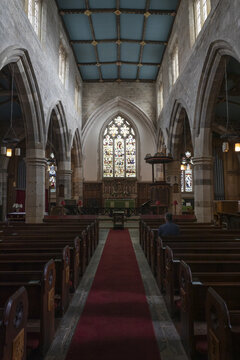 York, United Kingdom - 14 July 2026: View of the interior of a historic church in York with wooden pews, a red carpeted aisle, stone arches, and a vibrant stained glass window.