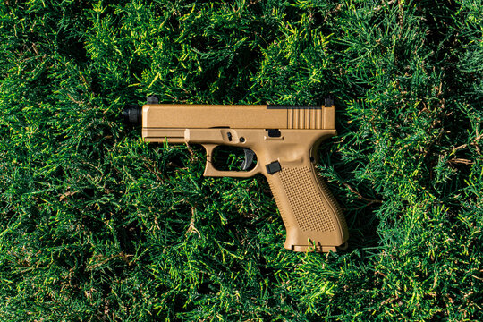 Desert tan pistol against green background