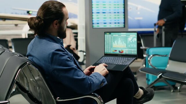 A business executive evaluates company data and KPIs on a laptop at the airport, comparing financial performance before departure with a runway view.
