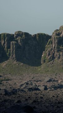 Rock formations stand tall in a vast area with sparse vegetation. The ground is rocky, and the scene captures the natural beauty of the terrain during clear daylight hours.