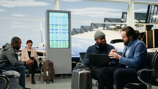 Manager and assistant use a laptop at the airport while preparing to attend an overseas company meeting and travel as a business delegation.