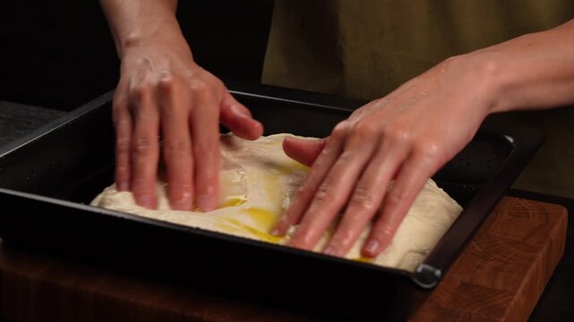 A chef in the kitchen places yeast dough onto a baking sheet (close-up).
