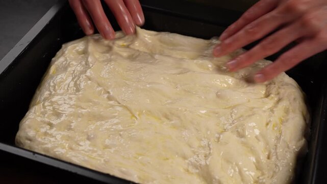 A chef in the kitchen places yeast dough onto a baking sheet (close-up).