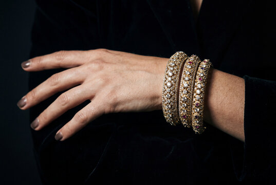 Elegant golden bangles set with gemstones on womans wrist