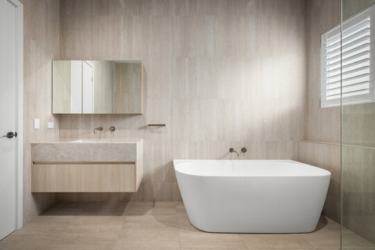 modern bathroom, freestanding bathtub, floating vanity, luxury bathroom, bathroom interior, contemporary design, stone tiles, bathtub, washbasin, mirror cabinet, glass shower, minimalist, neutral colo