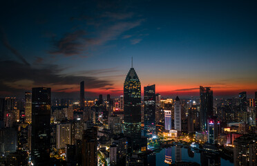 Obraz premium Aerial twilight view of Wuhan Financial Street CBD. The towering, illuminated skyscrapers reflecting in the water symbolize the dynamic growth of China's economy.