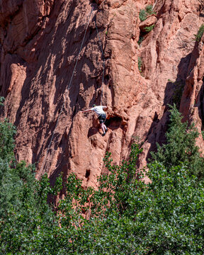 A rock climber is climbing on one of the steep rocks at Garden of the Gods under a sunny day