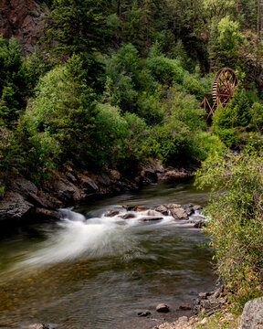Historic site with wooden Water Wheel and a Creek flowing between forests, Colorado