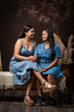 Sisters sitting together sharing a moment smiling indoors