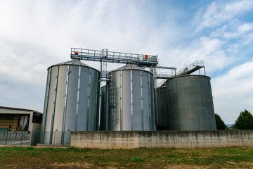 Grain storage silos at agricultural facility, metal cereal silos for wheat and corn, modern farming infrastructure, agribusiness logistics, food supply chain, harvest storage and industrial  © rikstock