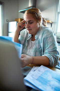 Stressed woman paying bills at home kitchen table