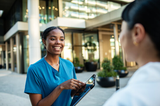Smiling nurse and doctor with tablet outside modern clinic