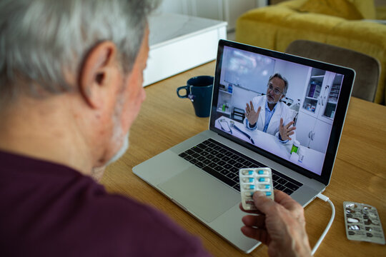 Senior man showing medication during online doctor consultation at home