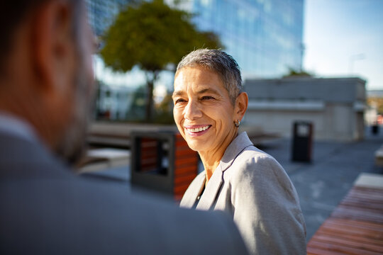 Smiling senior businesswoman talking with colleague outdoors