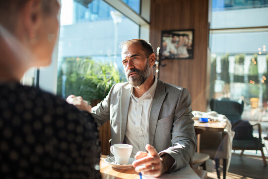 Mature businessman meeting client at coffee shop