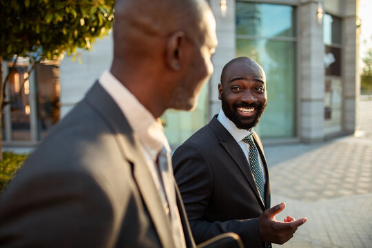 Two businessmen talking while walking downtown