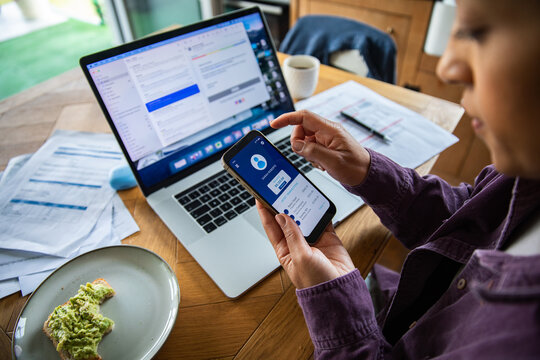 Young woman paying bills with mobile banking at home