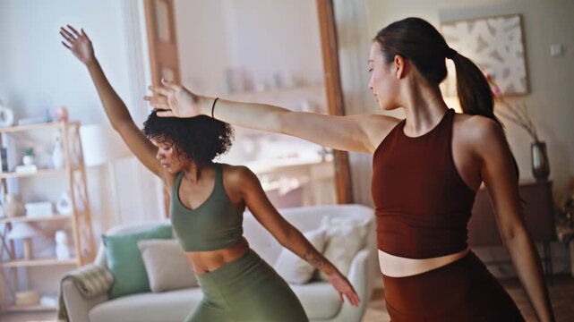 Two women practicing yoga triangle pose home. Fitness workout together morning.