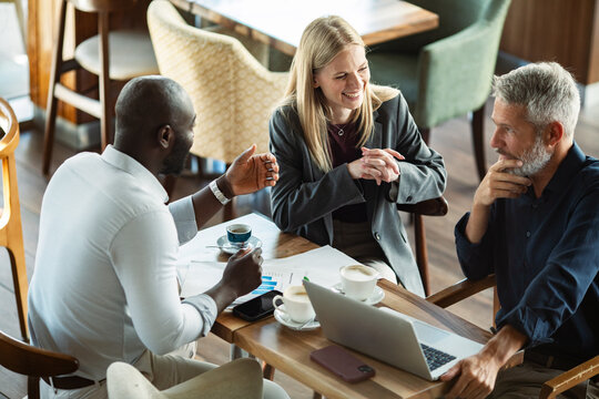 Diverse business team meeting over coffee in a cafe
