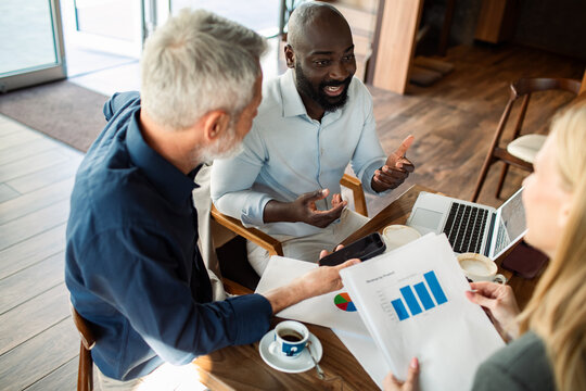 Colleagues discussing sales charts at a cafe meeting