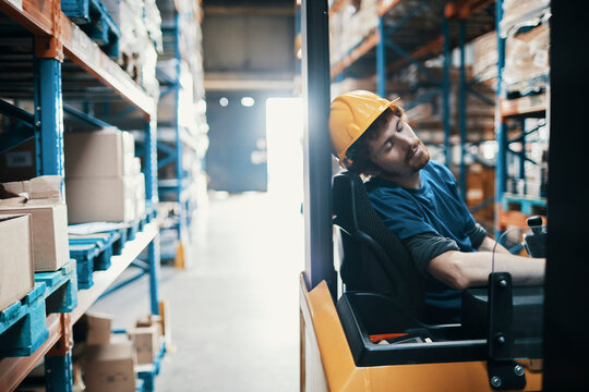 Tired forklift driver sleeping in warehouse
