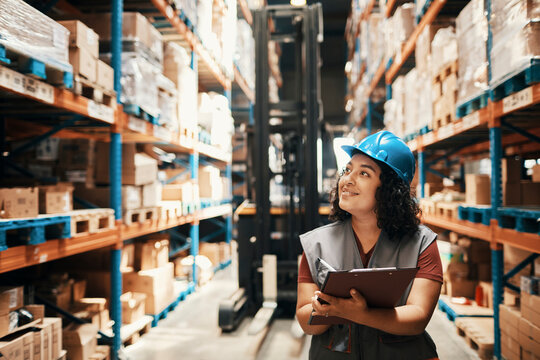 Female warehouse worker checking inventory with clipboard in distribution center