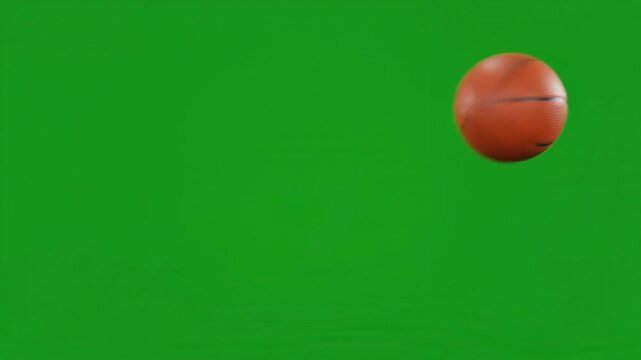 Overlay video transition, Orange basketball rolling across a bright green screen background for sports video production and chroma keying.