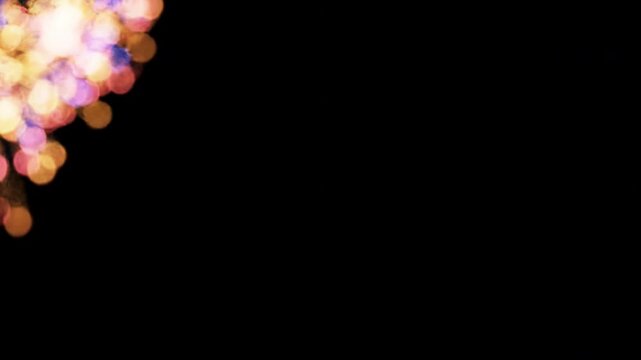 Abstract golden bokeh light particles glowing against a dark black background for festive celebrations and backgrounds.