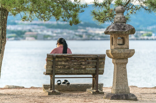 A asian girl sitting on a bench on sea bank