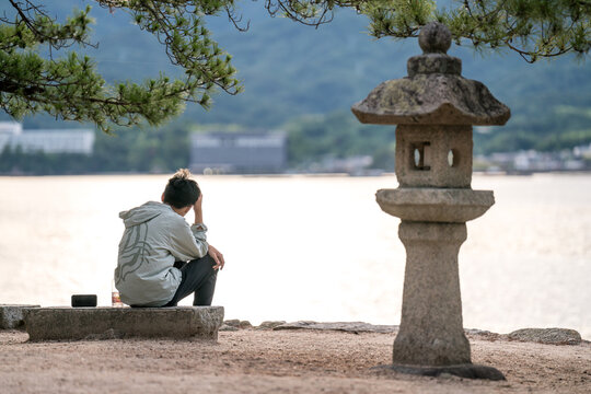 Worried Japanese teenager sitting on the seashore