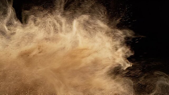 Overlay video transition, Dynamic explosion of brown powder particles isolated on a black background highlighting motion and texture.