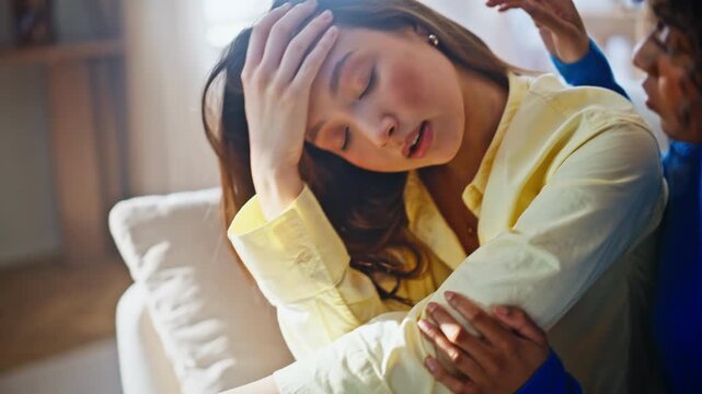 Upset woman consoled by caring friend home sofa. Emotional talk between friends.