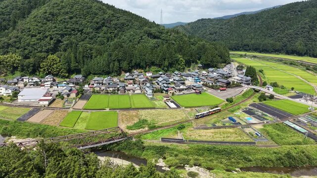 ドローンで撮る日本の風景　田園と山々に囲まれた集落を走る観光列車　美しくのどかな日本の田舎をゆっくり横移動する空撮