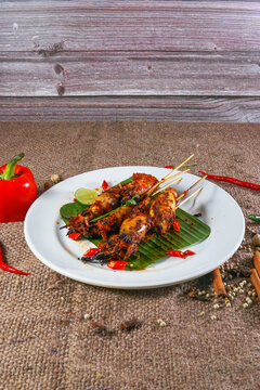 Grilled Squid Skewers with Padang Spices on Banana Leaf

Description
Skewered grilled squid coated in a rich reddish brown Padang style spice glaze rests on a fresh banana leaf atop a white plate, gar