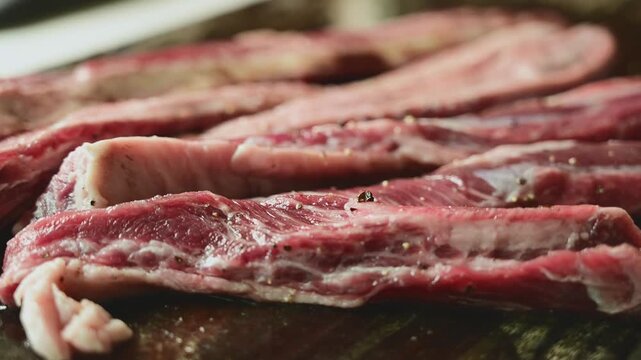 Seasoning Fresh Beef Strips with Salt on Wooden Cutting Board Before Cooking