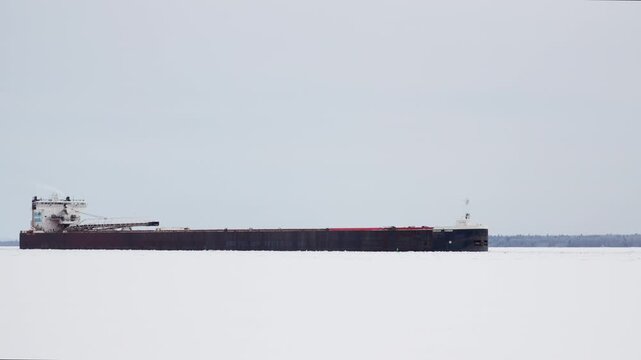 Great Lakes Freighter pushing through ice early in the shipping season. Static shot as they go down the Saint Mary's River.