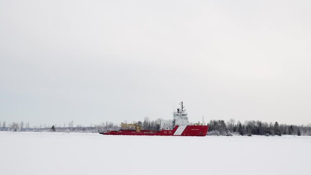 Canadian Coast guard breaking ice in the Great Lakes area. Static shot as they go down the St Mary's River