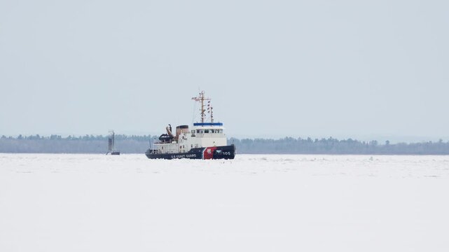 US Coast Guard breaking Ice in the Great Lakes Area. Panning shot as they go down the Saint Mary's River.