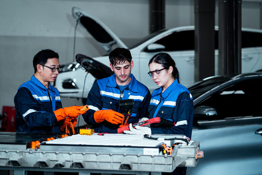 Professional team of automotive technicians working together in a modern vehicle repair workshop, teamwork, automotive maintenance, mechanical engineering, technical expertise and vehicle service i