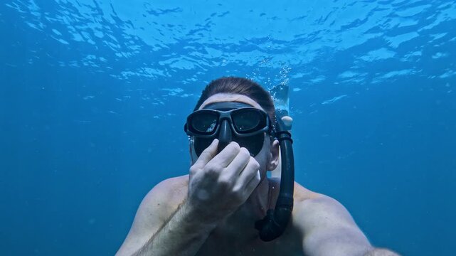 Male freediving underwater on the deep in blue ocean, selfie of freediver