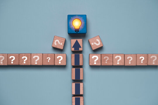 Problem solving concept with blocks forming a path from questions to a glowing light bulb for finding solutions, critical thinking, innovation, strategic planning, creativity and business success.