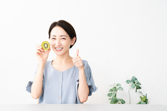 キウイフルーツを食べる女性　食べ物イメージ