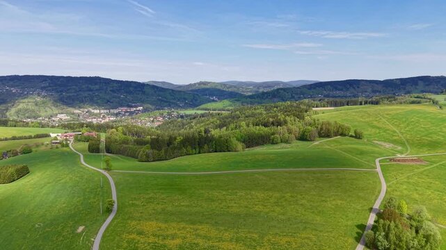Aerial view of a rural landscape no visible action static scene, in rural countryside with rolling hills and green fields, with hills, fields, roads, with green, blue accents, nearby objects.