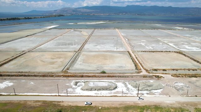 The Salterns of Messolonghi, Saltworks Area in Tourlida, Lagoon and Mountains in Background and Car Passing By, Aerial Panoramic Landscape, Trucking shot