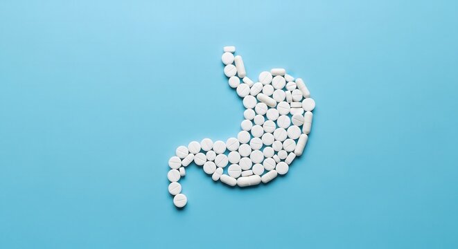 Human stomach shape made of white medical pills on blue
