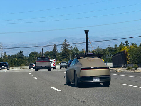 Tesla Robotaxi and Tesla Cybertruck, both fitted with roof-mounted camera and sensor equipment, travel in traffic on a multilane highway during road testing - California, USA - July 2, 2026