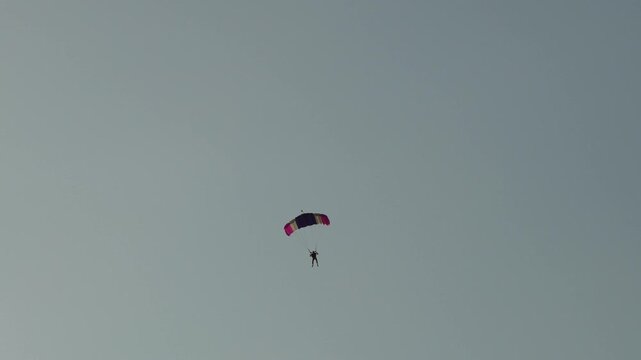 Parachutist descending with colorful canopy against sky