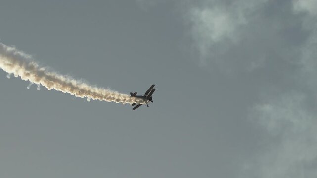 Biplane performing aerobatic stunt with smoke trail